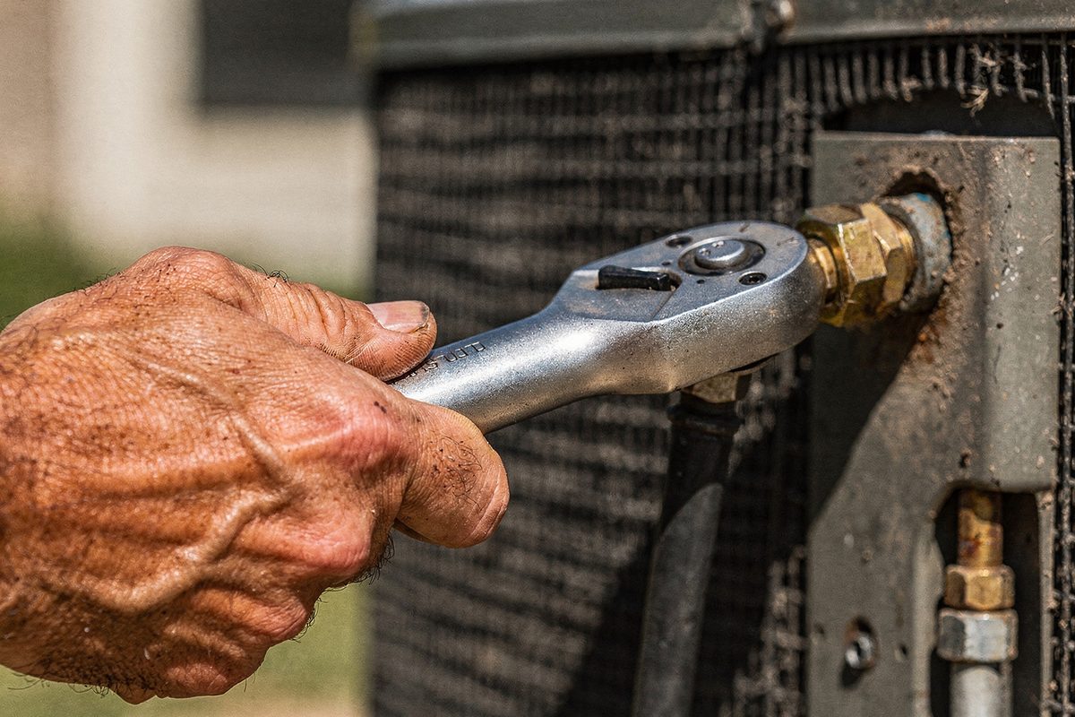 Technician using a torque wrench to tighten a refrigerant line fitting